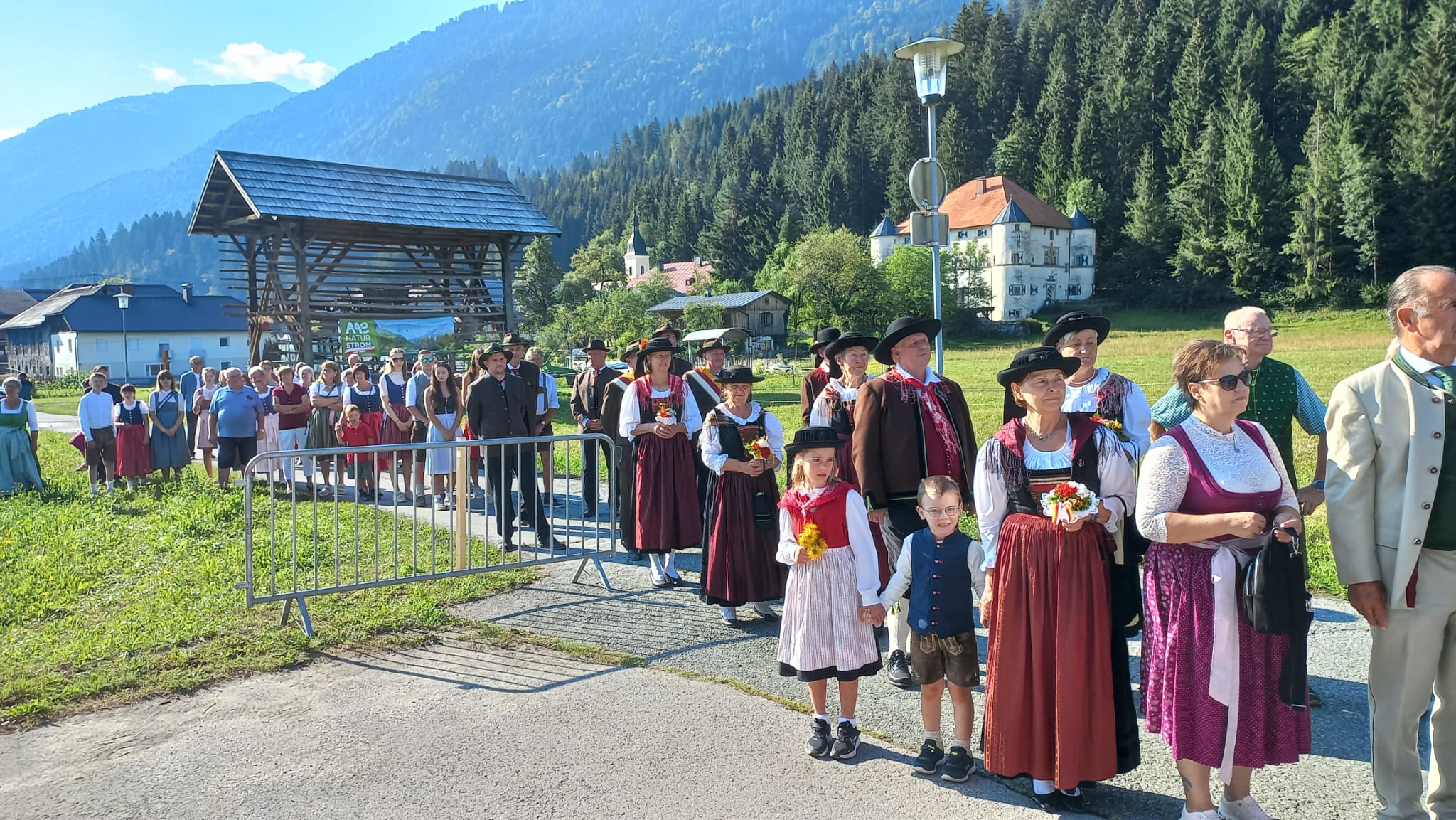 Trachtengruppe marschiert in einem Bergdorf in Österreich mit traditioneller Kleidung.
